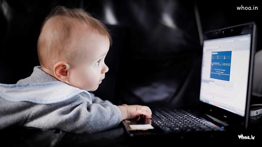 Cute Boy Baby Using Laptop Wearing Grey Color Dress In Dark