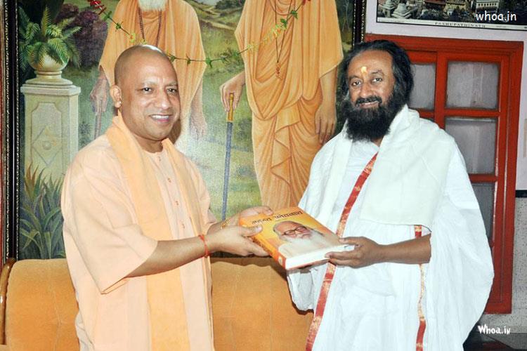 Yogi Aadityanath Is Giving A Book To Shri Shri Ravishanka