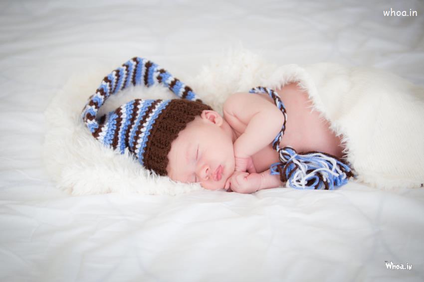 Cutesleeping Newborn Baby In The Bed With Wearing Little Cap