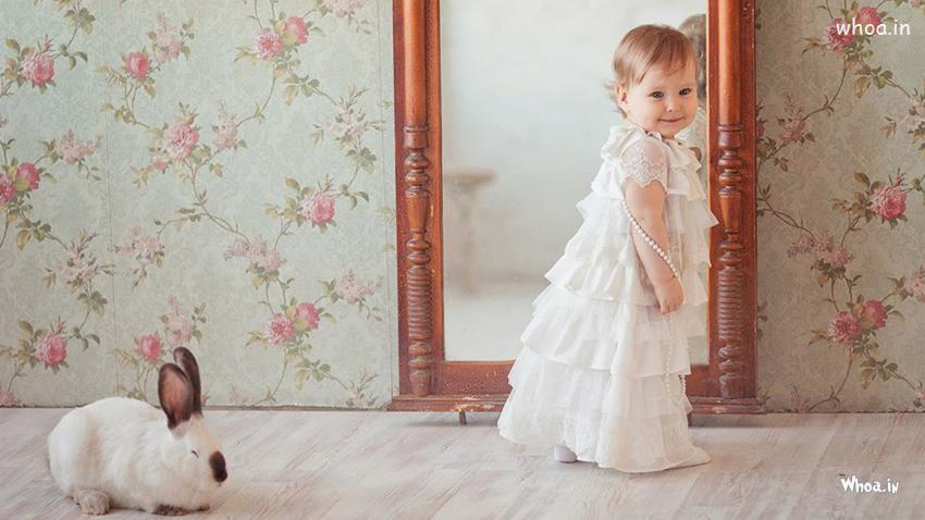 Prettiest Cute Baby Girl Is Standing Near Mirror White Dress